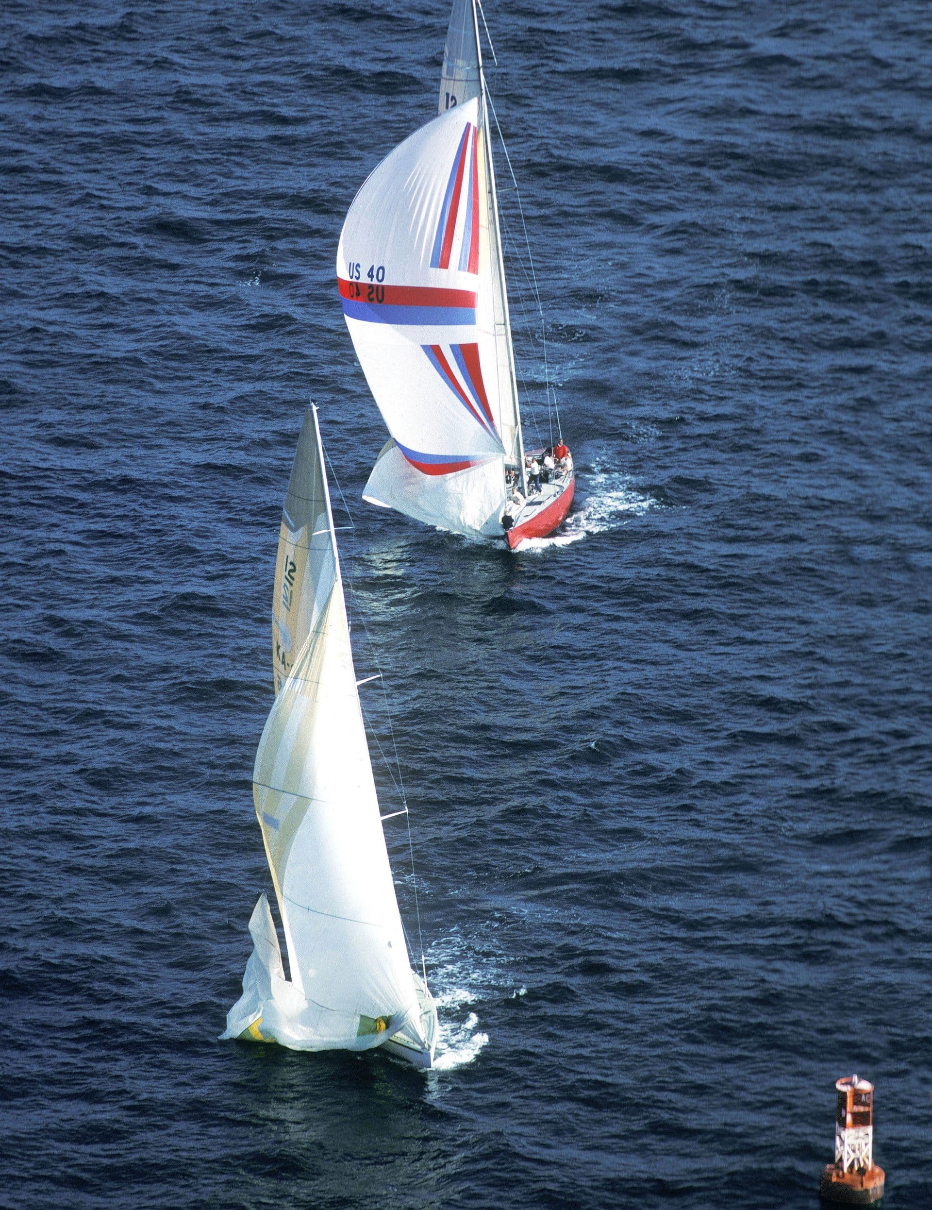 Australia II is about two boat lengths ahead of the other yacht as it approaches the orange buoy.