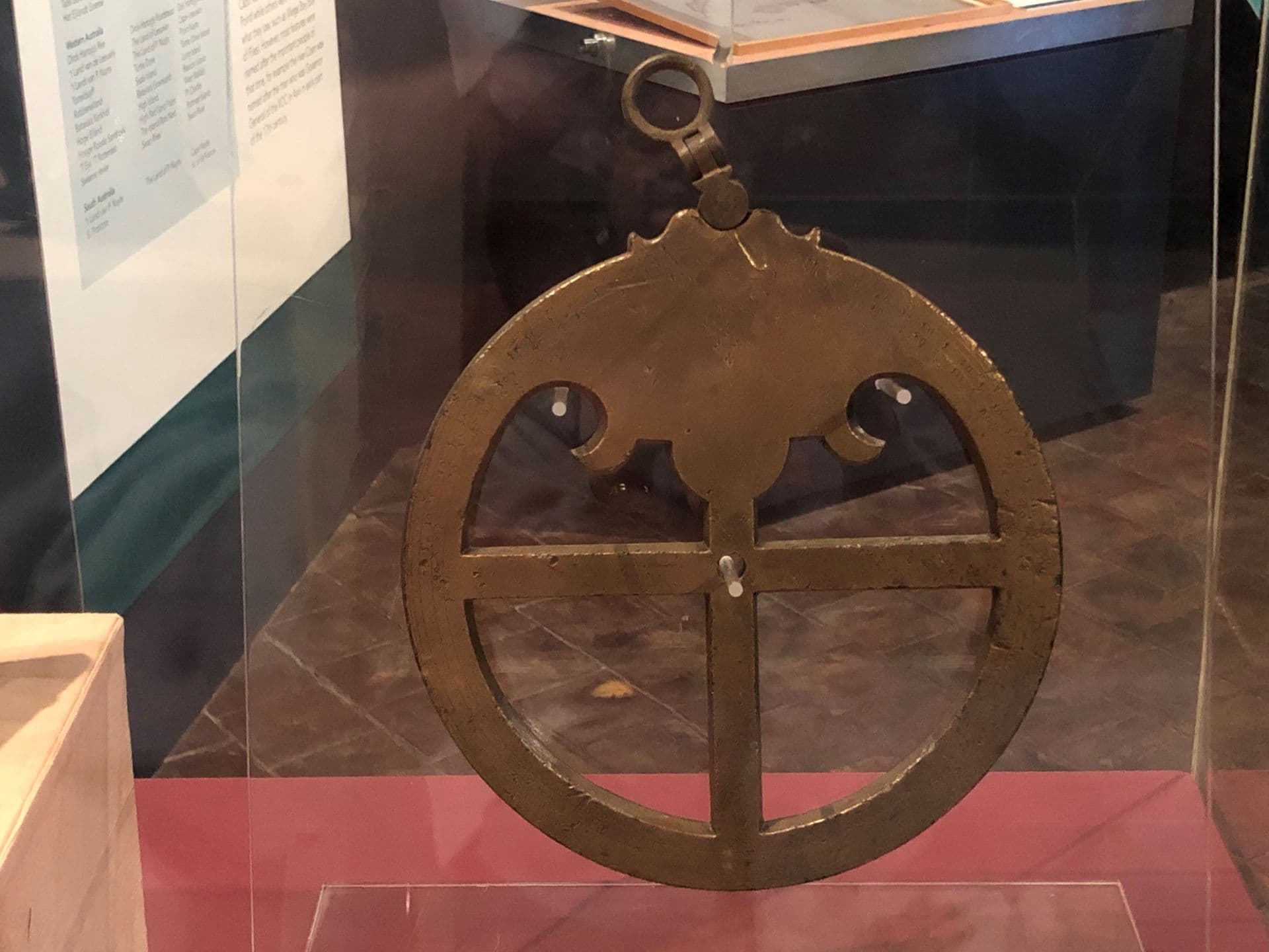 Heavy brass metal circular ring with cross through the middle displayed in glass cabinet.