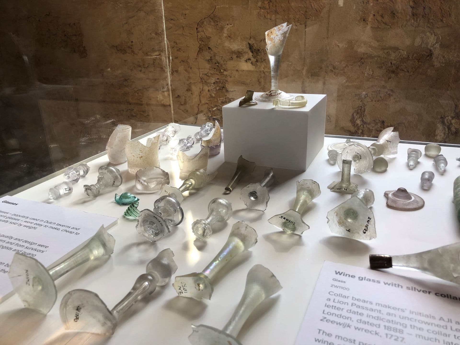 Pieces of broken glass objects laying in on a white surface in the cabinet.  Some pieces are bases to wine glasses.