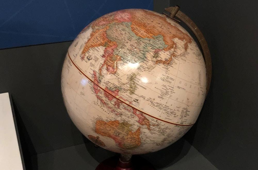 Round ball mounted on a stand with images of countries of the world printed on it.