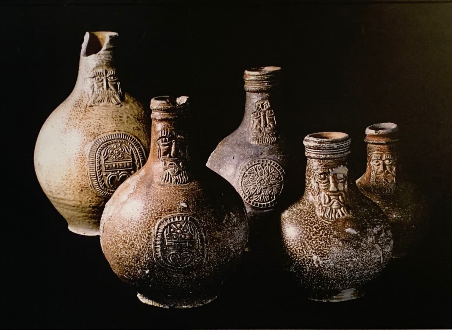 Five stoneware jugs of varying sizes featuring designs of bearded men.
