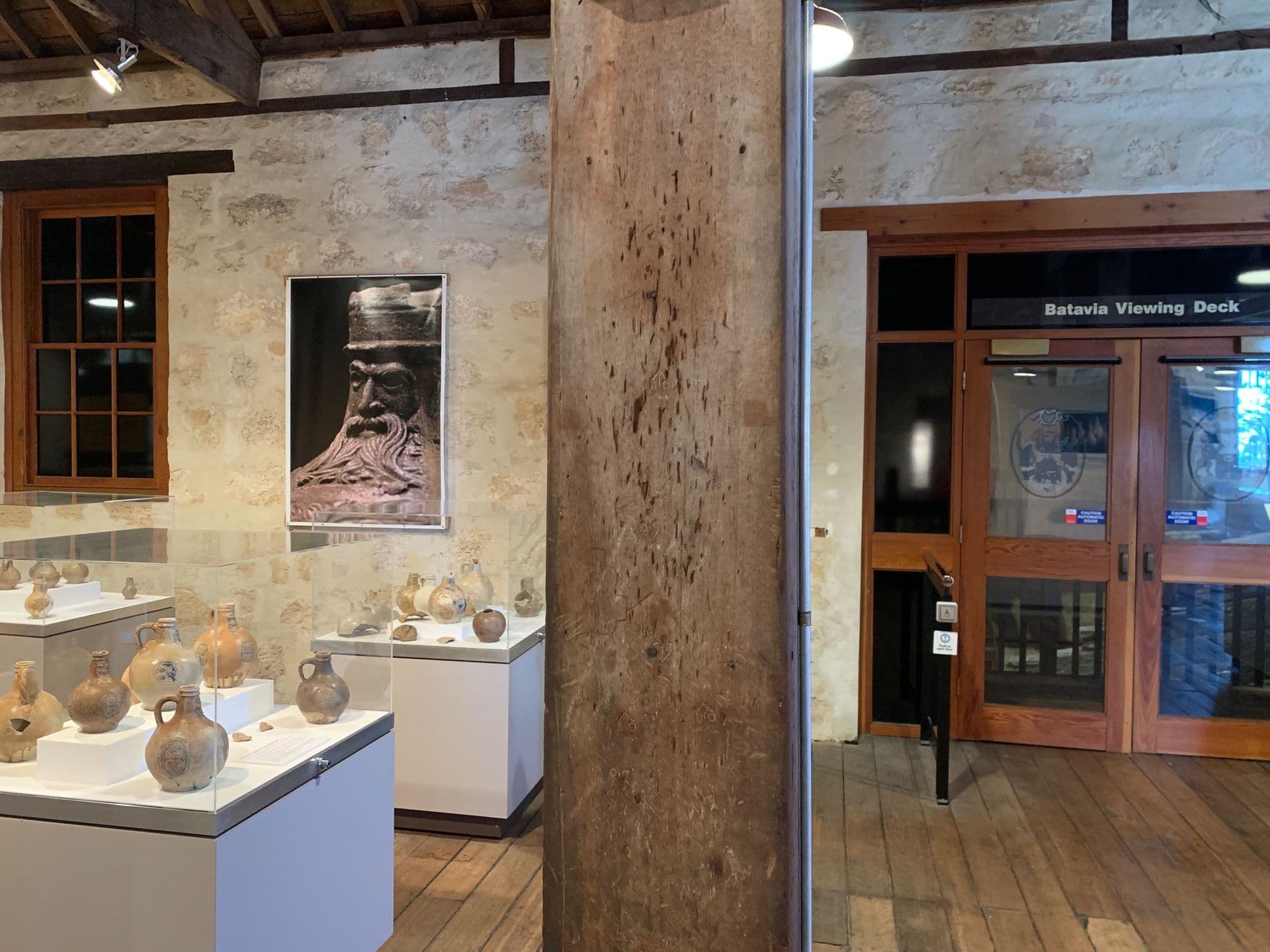 Image of a wooden column in a gallery, with many scratches and markings on it.