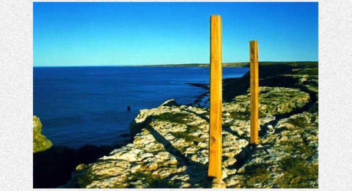 Two posts starting vertical on a cliff overlooking the water